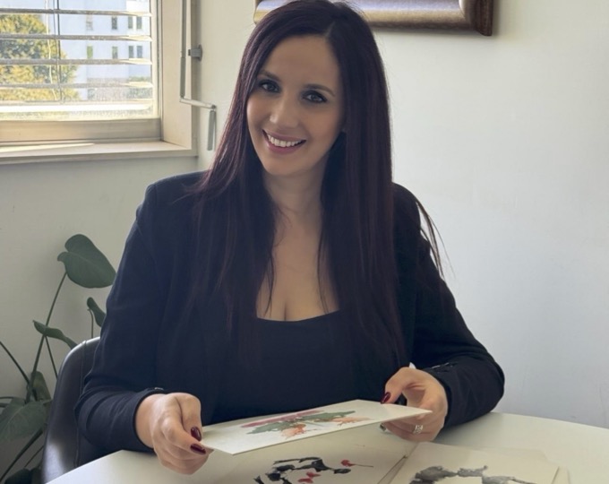 Joana Arantes sentada a uma mesa a segurar pranchas de manchas de tinta